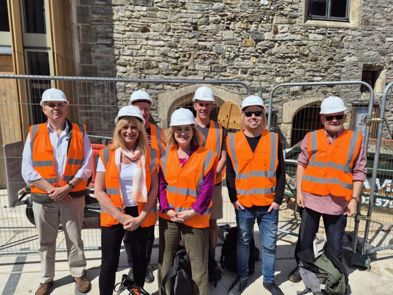 Image shows seven member of the new Board of Trustees standing outside Scaplen's Court with hard hats and high visibility jackets on.