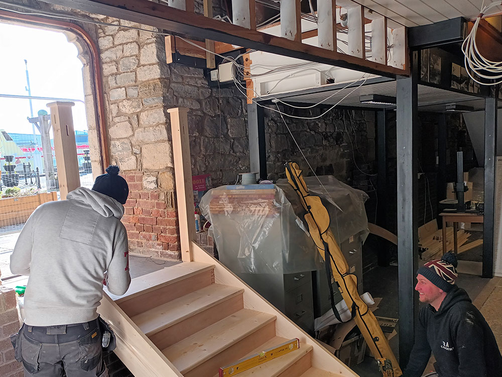 People constructing a wooden staircase inside a building