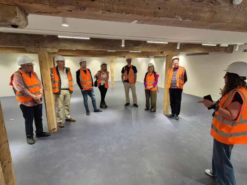 The new Board of Trustees standing in a new gallery space with hard hats and high visibility jackets on.
